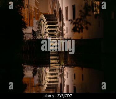 Blick auf das große Holzrad einer Wassermühle an der Moldau in der Altstadt von Prag. Ein Spaziergang durch die Stadt in einer warmen und wolkenlosen Herbstnacht. Stockfoto