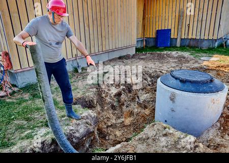 Der Arbeiter legt ein perforiertes Abflussrohr in einen Absorptionsgraben. Stockfoto