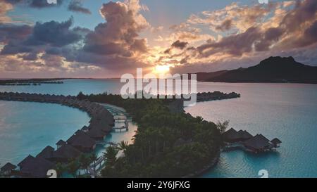 Luxuriöses Hotel mit Holzvillen in Korallenrifflagune. Exklusive Resort-Bungalows auf Bora Bora. Abgelegene romantische Flitterwochen, exotische Sommerreise. Drohnenflug aus der Luft. Fantastischer farbenfroher Sonnenuntergang Stockfoto