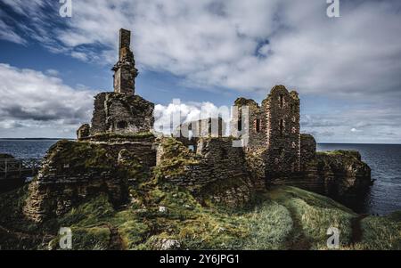 Ein malerischer Blick auf die Ruinen von Castle Sinclair Girnigoe an der Küste von Caithness, Schottland unter teilweise bewölktem Himmel. Stockfoto