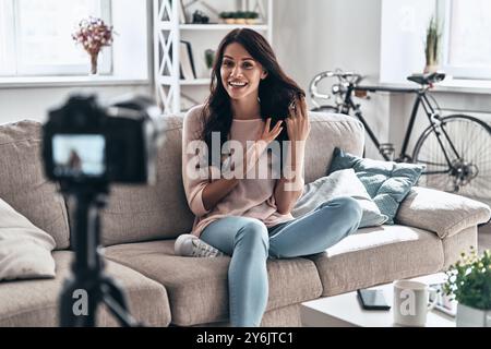Wir nehmen alles auf. Weibliche Vloggerin macht Social-Media-Videos, während sie drinnen sitzt Stockfoto