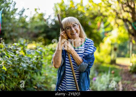 Porträt einer lächelnden Seniorin, die in ihrem Garten steht Stockfoto