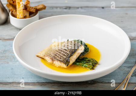 Gegrilltes Seebarschfilet mit Garnierungen in einem eleganten Restaurant Stockfoto