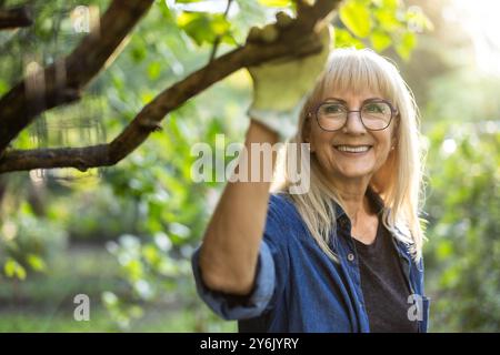 Porträt einer lächelnden Seniorin, die in ihrem Garten steht Stockfoto