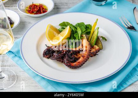 Gegrillter Tintenfisch mit Rucola und Mini-Gemüse auf einem weißen Porzellanteller Stockfoto