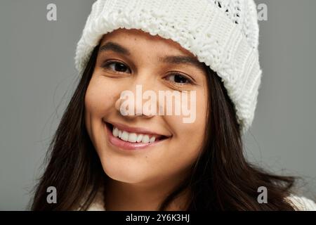 Eine hübsche junge Frau lächelt hell und drückt Freude aus, während sie in modischer Winterkleidung gekleidet ist. Stockfoto