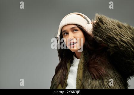 Eine junge Frau drückt ihre Emotionen aus, während sie modische Winterkleidung und Kopfhörer trägt. Stockfoto