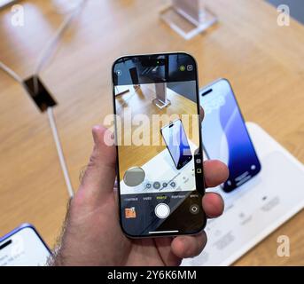 Paris, Frankreich - 20. September 2024: POV einer männlichen Hand, die das iPhone 16 Pro über einem Tisch hält, um das Kameramodul und die Funktionen zu testen Stockfoto
