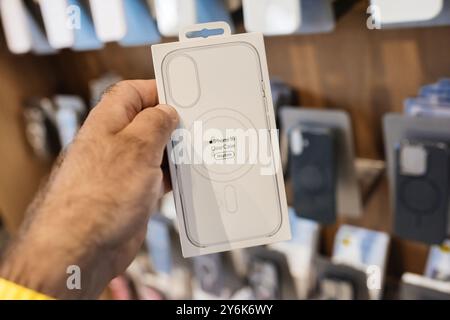 Paris, Frankreich - 20. September 2024: Eine männliche Hand hält die neueste durchsichtige Kunststoffhülle für iPhone 16 Plus mit MagSafe in einem Apple Store, dahinter sind Hüllen zu sehen Stockfoto