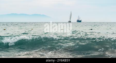 Segelboot und Schiff teilen sich eine ruhige Meereslandschaft. Seefahrt Serenity. Stockfoto