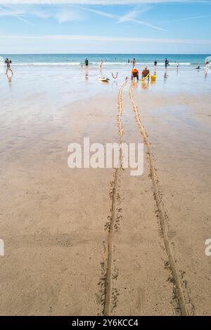 Zwei RNLI-Rettungsschwimmer sitzen in Stühlen und beobachten Urlauber im Meer bei Ebbe am GT Great Western Beach in Newquay in Cornwall in Großbritannien Stockfoto