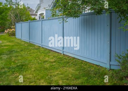 Großer neuer Holzzaun um das Haus und die Bäume. Harter Holzzaun mit grünen Bäumen und Weg. Zäune und Tore. Hochwertiger Zaun. Straßenfoto. Stockfoto