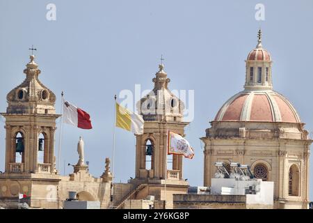 Nahaufnahme der Glockentürme und Kuppel einer Kirche mit Fahnen in Valletta, Malta. Stockfoto