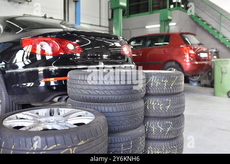 Reifenwechsel in einer Garage – Stapeln von Reifen im Vorder- und im Hintergrund auf der Hebebühne Stockfoto