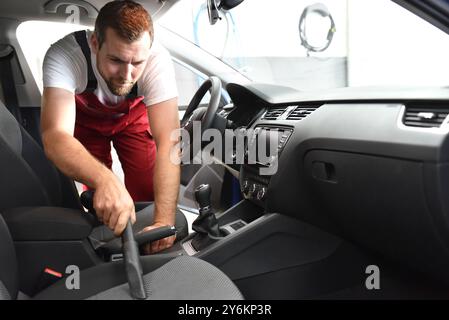 Professionelle Vorbereitung des Fahrzeugs in einem Auto waschen - Arbeitnehmer saugt die Innenraum Stockfoto