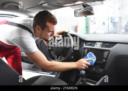 Ein freundlicher Mechaniker reinigt einen Autohändler im Autohändler für den Kunden Stockfoto