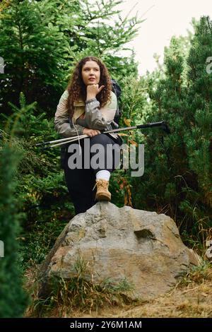 Eine Frau in Übergröße erkundet einen üppigen Wald und hält selbstbewusst inne, um ihre Umgebung zu schätzen. Stockfoto