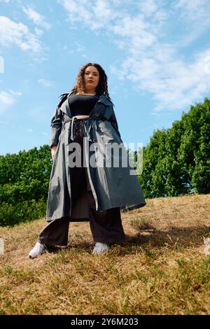 Eine schöne Frau in Übergröße steht anmutig in einem sonnendurchfluteten Feld, umgeben von üppigem Grün. Stockfoto