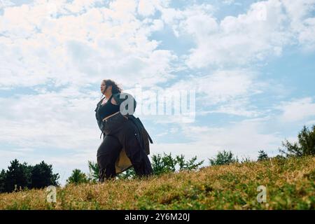 Eine schöne Frau in Übergröße steht selbstbewusst inmitten des grünen Feldes und des blauen Himmels. Stockfoto