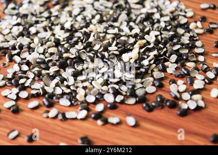 Split Black Linse auch bekannt als Black Gram, Black urad Dal, Vigna Mungo, urad Bean auf braunem hölzernem Hintergrund Stockfoto