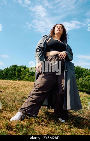 Eine wunderschöne Frau in Übergröße steht stolz auf einem üppigen Feld und sonnt sich im warmen Licht der Sonne. Stockfoto