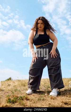 Eine große Frau posiert anmutig auf einem sonnendurchfluteten Feld, um die Schönheit der Natur zu genießen. Stockfoto