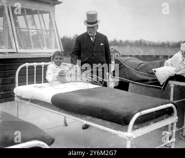 Gründertag im Alton Cripples Hospital, Hampshire. Sir William Treloar und ein kleiner Korbmacher. Auf einem Krankenhausbett auf der Terrasse sitzen und weben. Stockfoto