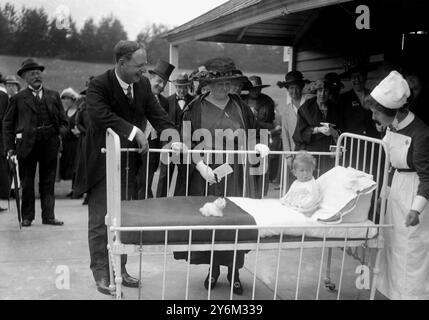 Gründertag im Alton Cripples Hospital. Dame Margaret Lloyd George und Sir Henry Gauvain, Kinderorthopädische Chirurgin am Krankenbett eines winzigen Patienten. Stockfoto