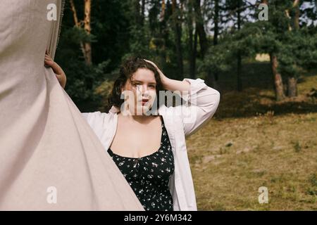 Eine schöne Frau in Übergröße steht anmutig in einem sonnendurchfluteten Feld, umgeben von Natur. Stockfoto