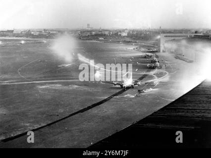 Dies ist ein allgemeiner Blick auf den Flughafen Tempelhof bei Nacht. Die C-54 sind im Vordergrund zu sehen und entladen ihre Fracht. Lichtstreifen oben rechts wurden durch die Scheinwerfer eines Flugzeugs erzeugt, das während der Zeitexposition zur Landung kam. Berlin 6. August 1948 Stockfoto