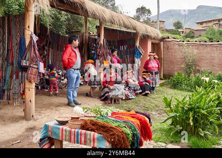 Ein lebhafter Andenmarkt in Chincero zeigt Menschen in traditioneller Kleidung, umgeben von farbenfrohen Textilien und handgefertigtem Kunsthandwerk, das kulturelle Leben widerspiegelt Stockfoto