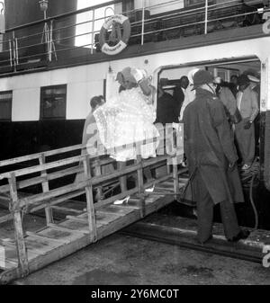 Southampton Hampton: Diese jamaikanische Frau bedeckt ihren Kopf vor dem Regen, als sie die Gangway des zarten 'Balmoral' hinunterkommt, gefolgt von anderen Passagieren heute, mit ihrem Kleid, das vom Wind umhergeweht wird. Die „Balmoral“ hatte die Immigranten aus ihrem Schiff geholt, das wegen schlechtem Wetter in Cowes Roads vertäut war. Der Immigrant hatte bei gutem Wetter die Westindischen Inseln im 'Montserrat' verlassen, aber bei der Ankunft hier regnete es sehr stark und viele hatten nur leichte Sommerkleidung. 24. Oktober 1961 Stockfoto