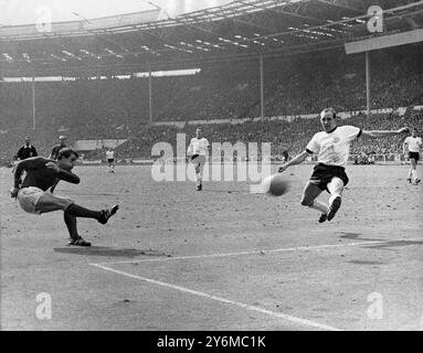 Hurst führt England auf die Siegerpiste, die ihm charakteristisch die Wangen aufbläht, und Geoff Hurst schleudert den Ball an Wili Schulz (Westdeutschland) vorbei, um Englands drittes Tor in der Verlängerung des WM-Finales in Wembley zu erzielen. In der Mitte gewann Franz Beckenbauer England 4-2 Stockfoto