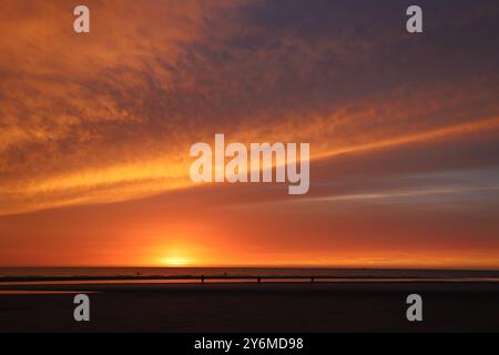 Wunderschöner Sonnenuntergang am Strand von Sankt Peter Ording mit einem bewölkten Himmel in Orangetönen Stockfoto