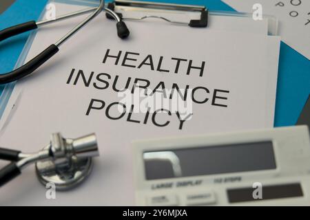 Richtliniendokumente, Stethoskop und Rechner symbolisieren Gesundheitskosten und Deckungsentscheidungen. Stockfoto