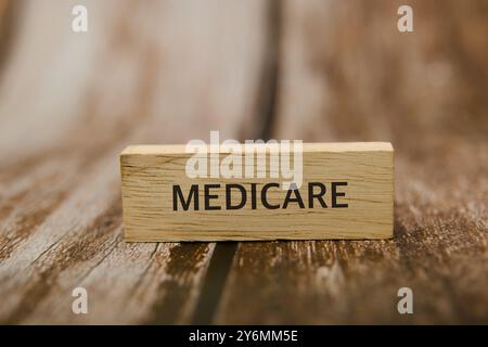 Einfacher Holzblock mit dem Wort „MEDICARE“ auf einer rustikalen Oberfläche. Krankenversicherungs- und Seniorenkonzept. Stockfoto