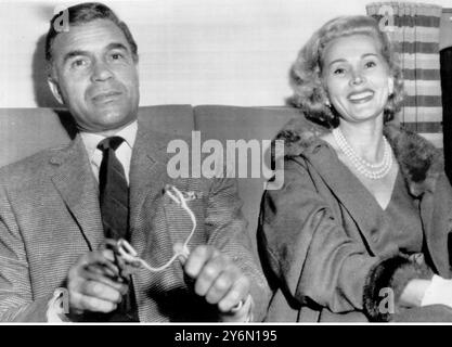 Los Angeles: Der dominikanische Playboy-Diplomat Porfirio Rubirosa zielt spielerisch auf den Kameramann, während er und die Schauspielerin Zsa Zsa Gabor sich auf den Start nach New York vorbereiten. Miss Gabor wird sich kurz nach Paris begeben, um dort einen Film zu drehen. Rubirosas Ambitionen wurden kürzlich von der Regierung der Vereinigten Staaten zerschlagen, die ihm die Arbeitserlaubnis verweigerte, einen Western-Film mit Miss Gabor zu drehen. September 1955 Stockfoto