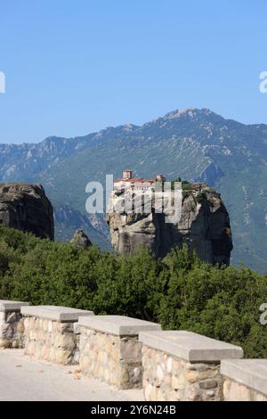 Ein atemberaubender Blick auf das Kloster der Heiligen Dreifaltigkeit in Meteora, Griechenland, das auf einer felsigen Klippe mit bergigem Hintergrund thront. Stockfoto