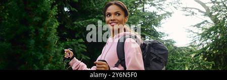 Eine junge Frau nimmt das Abenteuer des Wanderns in einem bunten Herbstwald auf, der in ihrem fröhlichen Moment festgehalten wird. Stockfoto