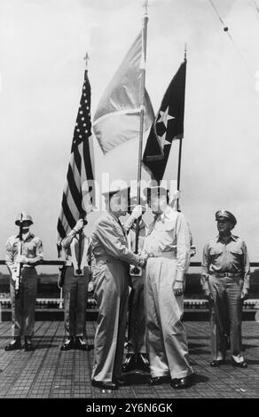 MacArthur unter UN-Flagge. General J Lawton Collins (L) Stabschef der United States Army, der dem General der Armee Douglas MacArthur, dem Oberbefehlshaber der Streitkräfte der Vereinten Nationen, der sich der nordkoreanischen Invasion in Südkorea widersetzt, die Hand schüttelte, als er ihm in Tokio eine Flagge der Vereinten Nationen schenkte. Die Präsentation fand auf dem Dach des Dai Ichi-Gebäudes statt, dem Hauptquartier von General MacArthur. Die UN-Flagge ist im Hintergrund zu sehen, flankiert von Amerikas Sternen und Streifen und General MacArthurs fünf-Sterne-Flagge. 1950 Stockfoto