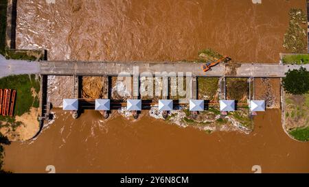 Aus der Vogelperspektive auf die Schleusen des Damms mit schnellem Wasserfluss in der Regenzeit. Stauwasser wird freigesetzt, Überkapazität nach starkem Regen. Stockfoto