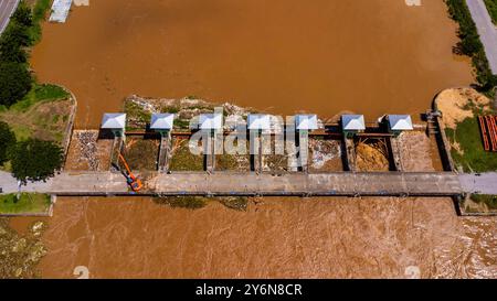 Aus der Vogelperspektive auf die Schleusen des Damms mit schnellem Wasserfluss in der Regenzeit. Stauwasser wird freigesetzt, Überkapazität nach starkem Regen. Stockfoto