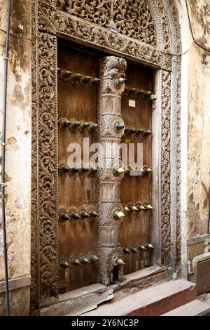 Eine aufwändig geschnitzte Holztür mit kunstvollen Details, die den traditionellen architektonischen Stil des historischen Sansibar zeigt. Die Handwerkskunst ist hoch Stockfoto