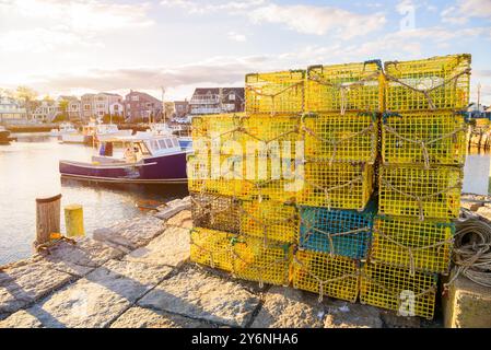 Stapel Hummertöpfe an einem Steinkai in einem Fischerhafen bei Sonnenuntergang im Herbst Stockfoto