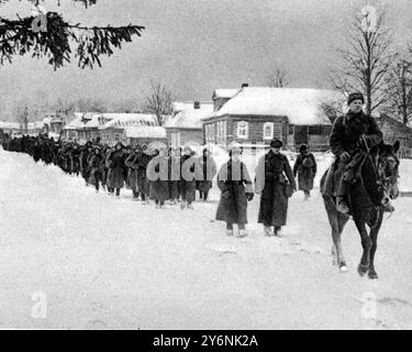 Der russische Vormarsch: Rauch und Flamme und deutsche Gräber im nördlichen Teil der Russischen Front marschieren Truppen der Roten Armee an einer von den Deutschen befreiten Siedlung vorbei. Januar 1942 ©2004 Credit:Topfoto Stockfoto