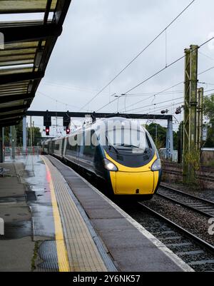 Der schlanke Personenzug nähert sich unter stimmungsvollem Himmel und spiegelt das Tempo und die Konnektivität des Stadtverkehrs wider. Stockfoto