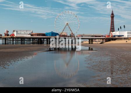 Ruhiger Blick auf den Strand mit ikonischem Riesenrad und Turm, der auf nassem Sand reflektiert wird. Stockfoto