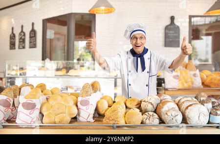 Überglückter Bäcker, der die Daumen in einer Bäckerei nach oben zeigt Stockfoto