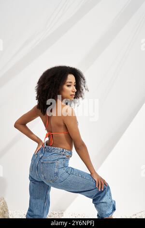 Eine junge Frau zeigt ihr Gespür für Mode mit einem stylischen Outfit ohne Rücken und Jeans. Stockfoto