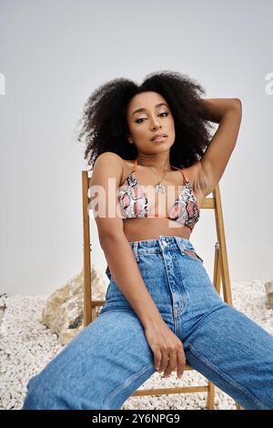 Eine modische junge afroamerikanische Frau sitzt selbstbewusst in stilvollem Outfit und strahlt Charme aus. Stockfoto